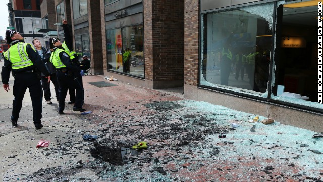 Boston police look at blown-out windows. The bombs shook buildings, sending people to seek shelter under tables, witnesses said.